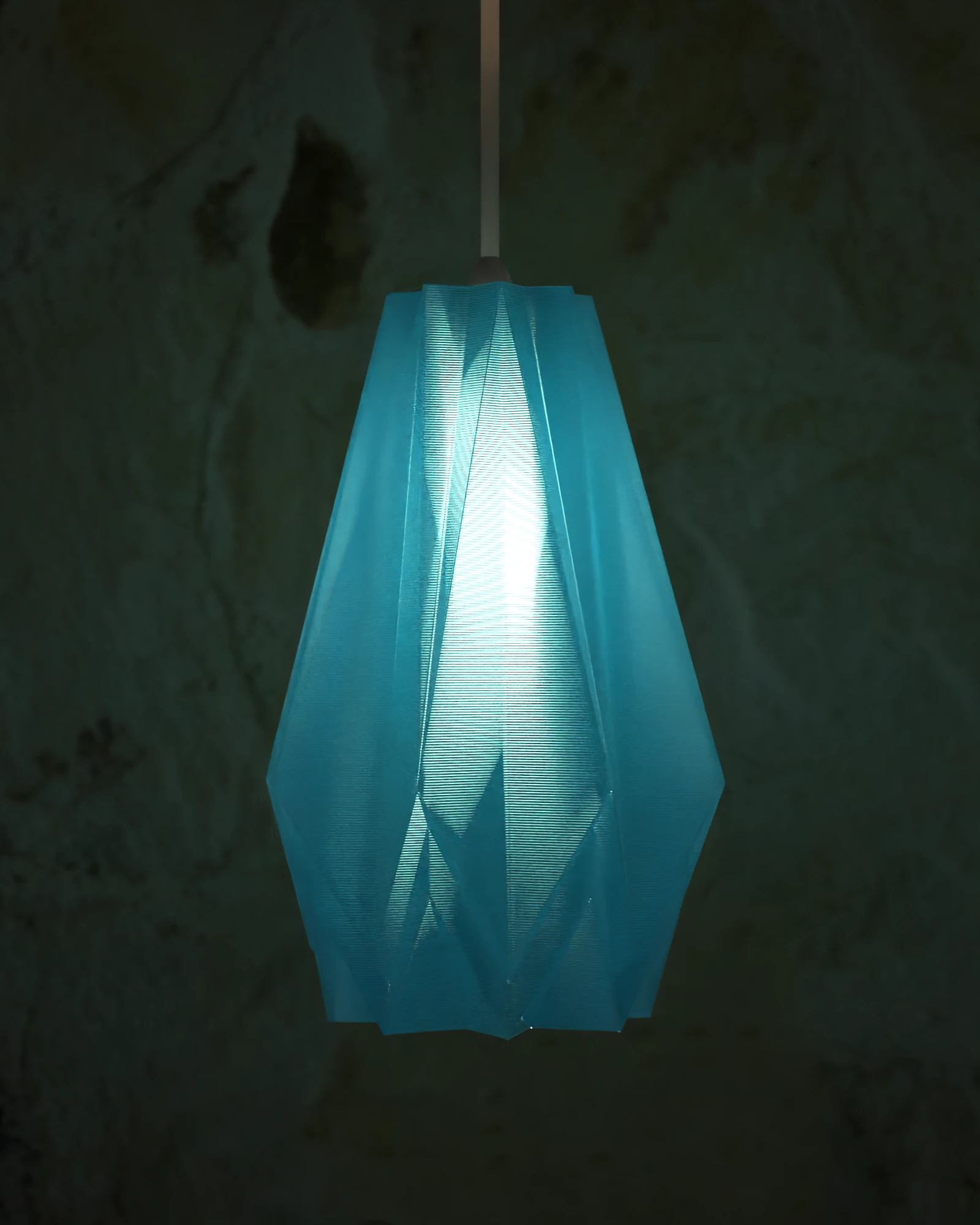 Lámpara GAMI en Azul Traslúcido encendida junto a una pared de piedra