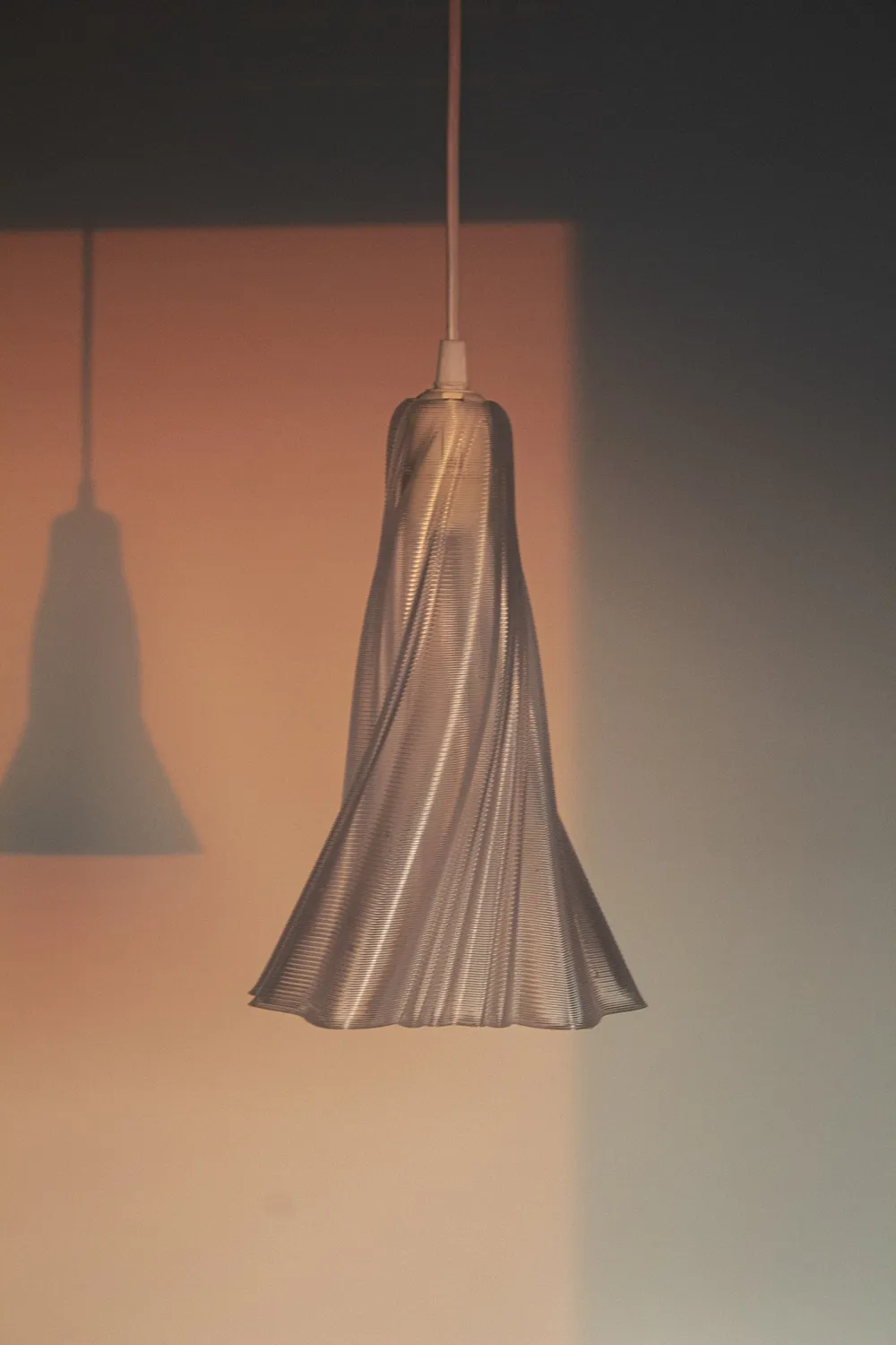 Lámpara YASHI Transparente al atardecer, con su sombra en la pared